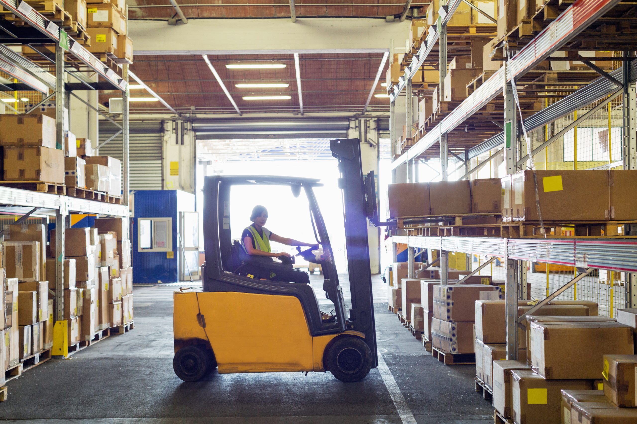 Silhouetted forklift truck at work in distribution warehouse